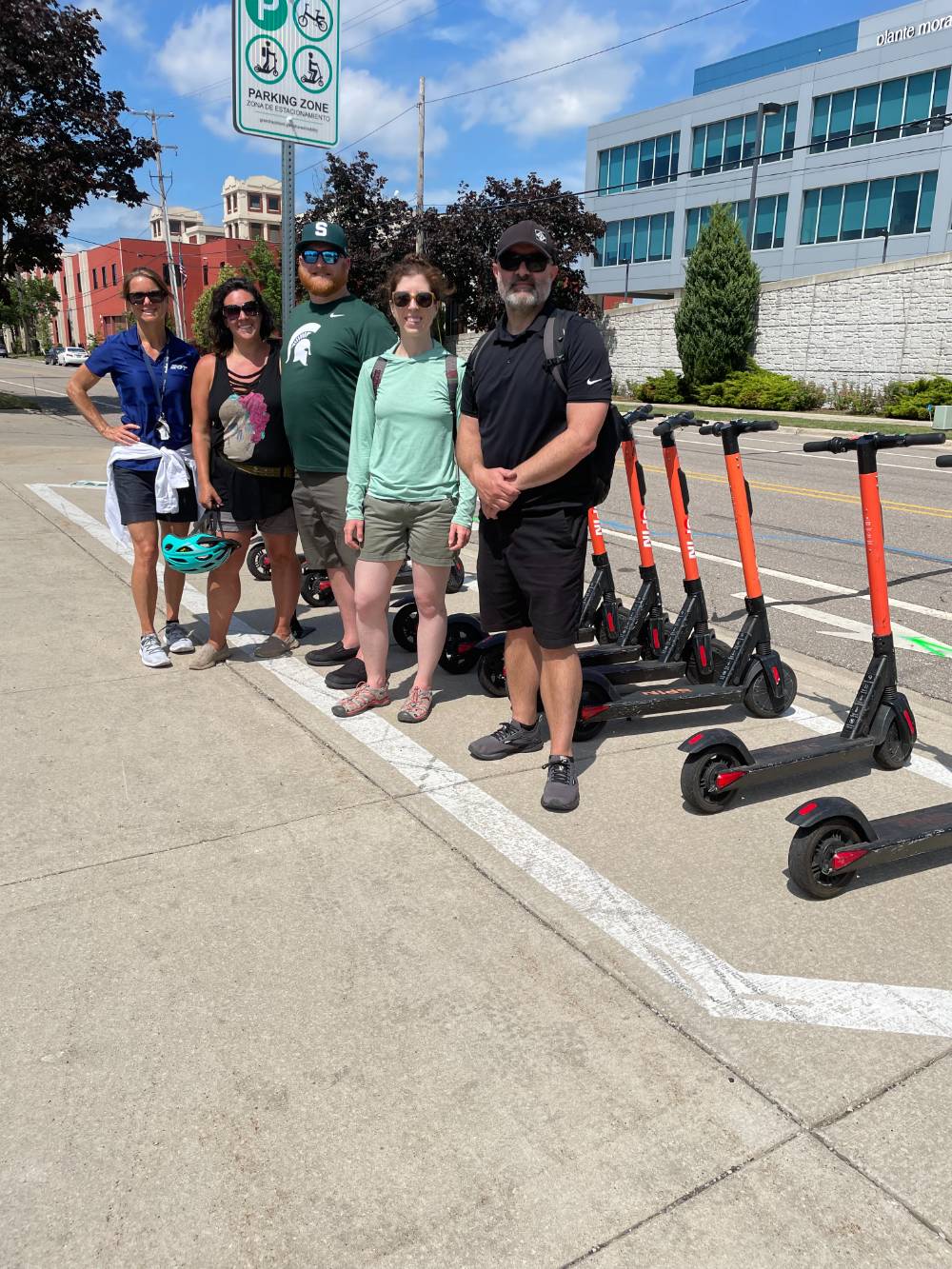 5 people standing by scooters